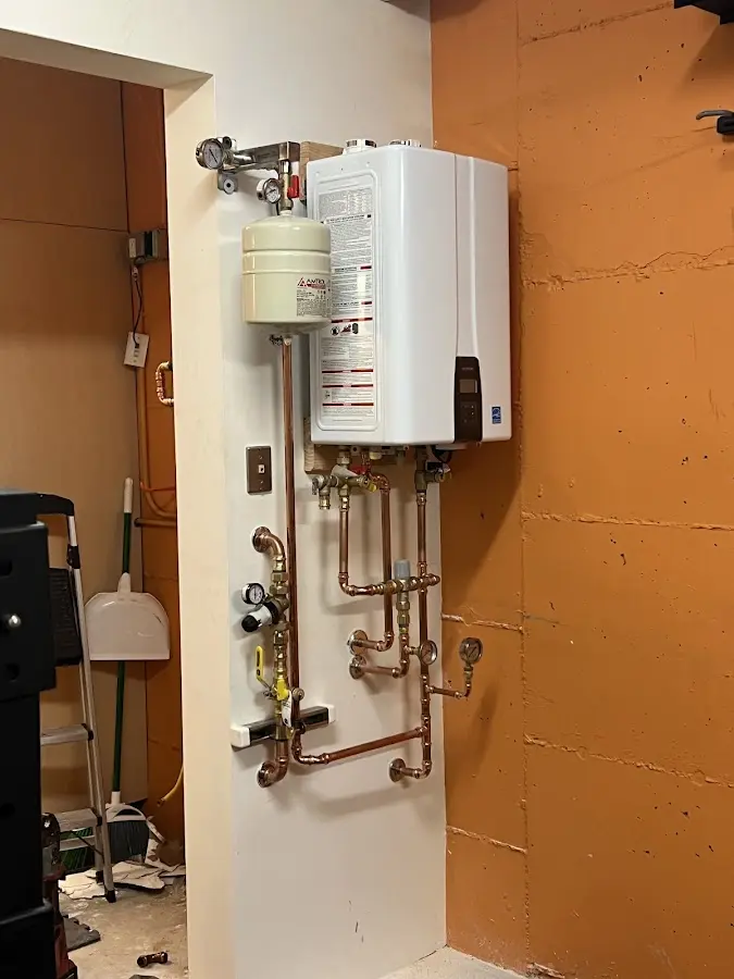 Plumbing technician inspecting water heater connections in East Providence